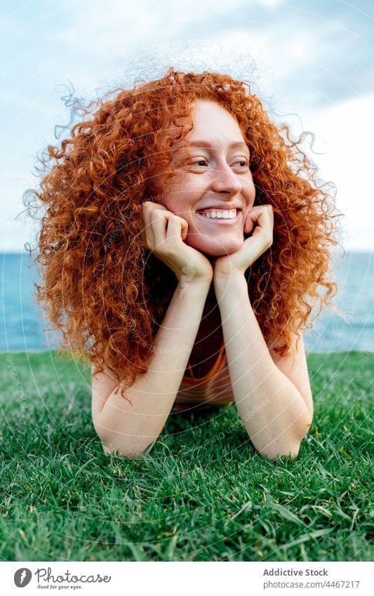 Fröhliche, rothaarige Frau im Gras liegend Glück sorgenfrei Rasen MEER sich[Akk] entspannen expressiv Sommersprosse Ingwerhaar Zahnfarbenes Lächeln jung Lügen