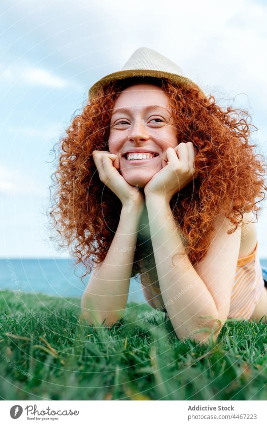 Fröhliche, rothaarige Frau im Gras liegend Glück sorgenfrei Rasen MEER sich[Akk] entspannen Sommersprosse Ingwerhaar Zahnfarbenes Lächeln Hut jung Lügen
