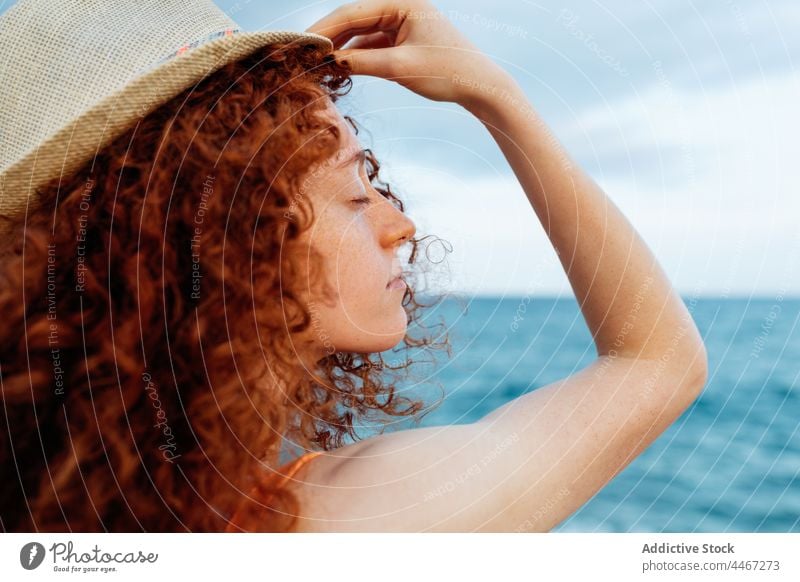 Frau mit Hut und geschlossenen Augen am Meeresstrand Tierhaut Deckblatt Küste MEER Sommersprossen Körperhaltung spielerisch friedlich Augen geschlossen genießen