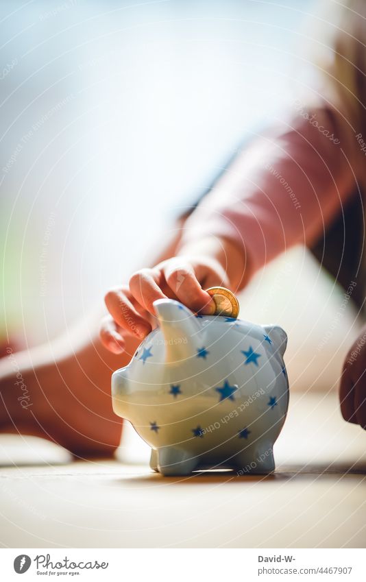 Kind wirft einen Euro in ein Sparschwein - Konzept - sparen Kindererziehung Spardose Geld Zukunft Münze stecken Taschengeld Kindheit Hand