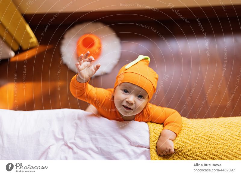 Glückliches einjähriges Baby im orangefarbenen Halloween-Kostüm zu Hause weinen Gas Gesundheit neugeboren Pflege Haut Kind Kürbis Tracht