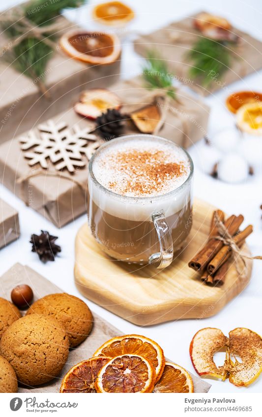 Cup of Latte Coffee mit Zimt und Weihnachtsgeschenke, dekoriert getrocknete Früchte, Tannenzapfen und Tannenzweige. Gemütliche Winterurlaub Hintergrund. Werbung