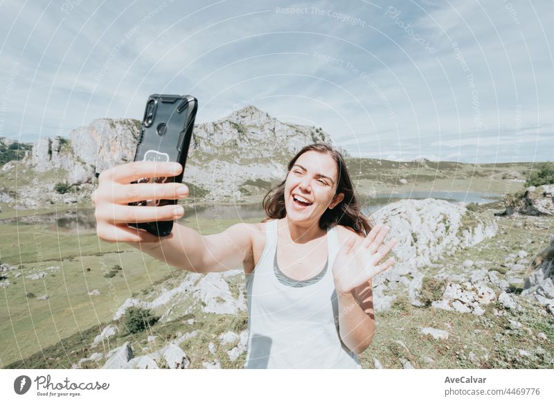 Fröhliche nette Frau, die lächelt und ein Selfie macht, während sie sich auf den Berghügeln ausruht, heller Tag an den Seen auf dem Gipfel der Berge, Friedenszeichen