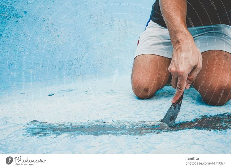 Nahaufnahme eines Mannes, der den Boden eines Schwimmbeckens repariert Flugzeugwartung Riss diy Spachtelmasse Pool Kittmesser Palette Arbeit Job heimwärts