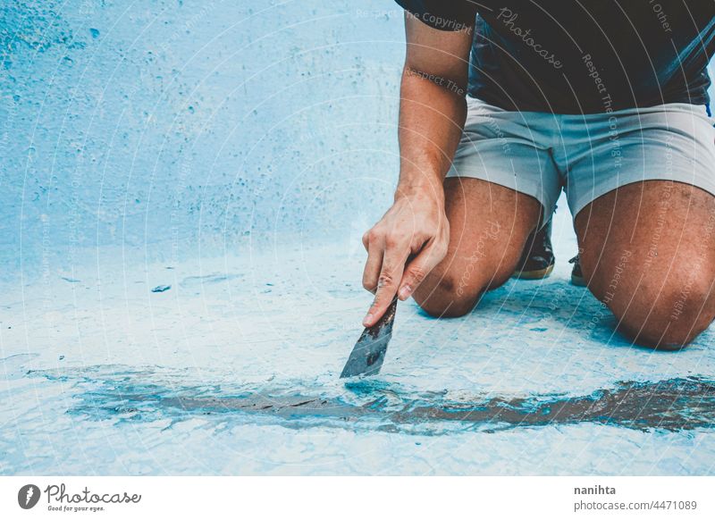 Nahaufnahme eines Mannes, der den Boden eines Schwimmbeckens repariert Flugzeugwartung Riss diy Spachtelmasse Pool Kittmesser Palette Arbeit Job heimwärts