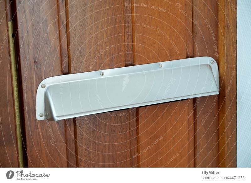 Alter Briefschlitz aus Aluminium an einer Holztür. Post Briefkasten Kommunizieren Detailaufnahme einwerfen Schlitz Wand schreiben Metall Haus Postfach