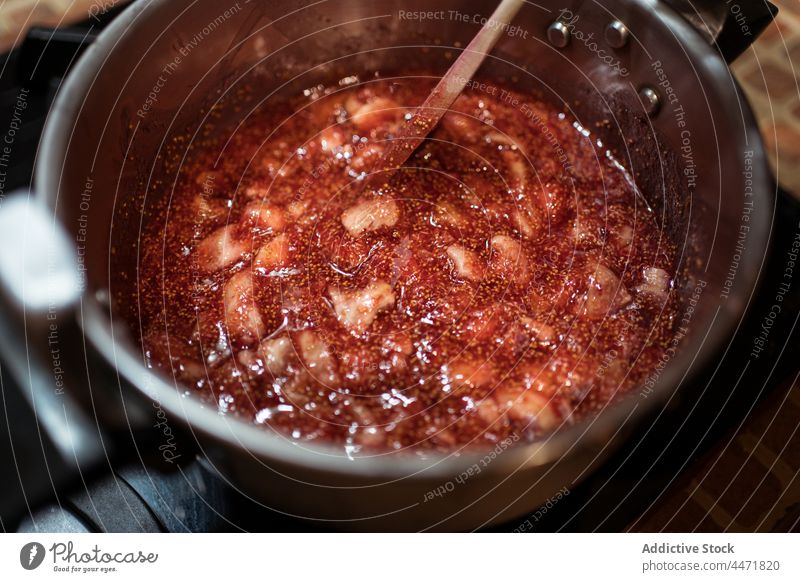Crop-Person bei der Zubereitung von Feigenmarmelade im Schnellkochtopf in der Küche vorbereiten Marmelade rühren natürlich süß kulinarisch Rezept Kocher