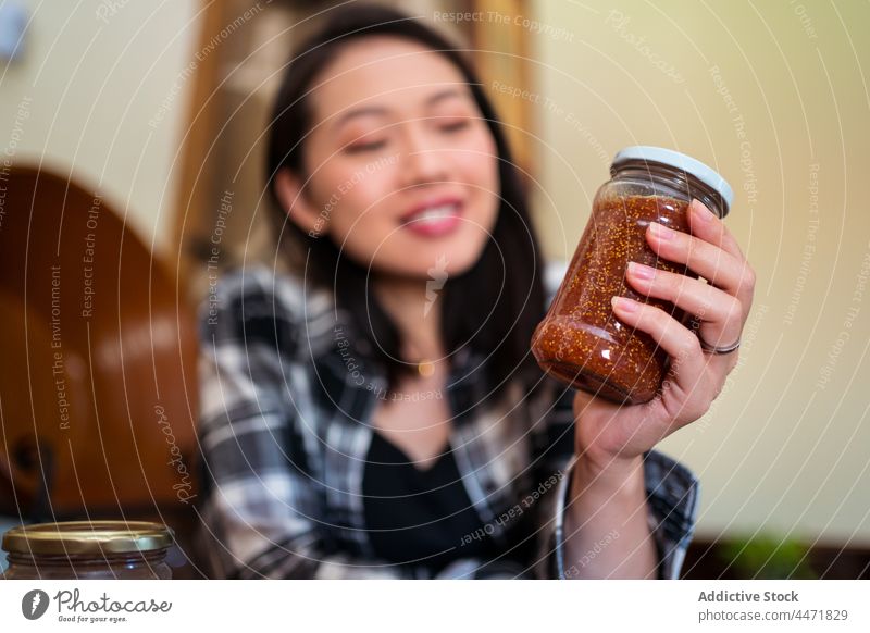 Asiatische Frau mit einem Glas Feigenmarmelade zu Hause Marmelade süß Leckerbissen natürlich organisch lecker selbstgemacht Frucht heimwärts geschmackvoll