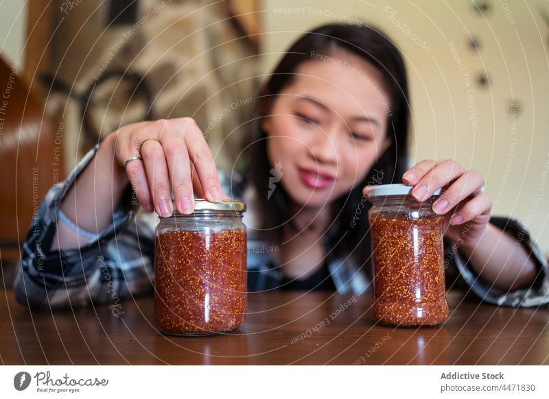Asiatische Frau mit Gläsern von Feigenmarmelade zu Hause Glas Marmelade süß Leckerbissen natürlich organisch lecker selbstgemacht Frucht heimwärts geschmackvoll