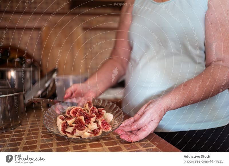 Crop alte Frau mit frischen Feigenscheiben in der Küche Frucht natürlich kulinarisch Vitamin Scheibe reif süß heimwärts Sehne organisch geschält Rezept duftig