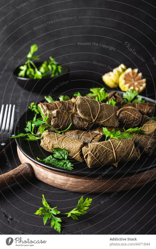 Teller mit leckerem Sarma-Gericht mit Petersilie und Zitrone Gabel Messer schmackhaft dolma Fleisch Traube Blätter Speise geschmackvoll Küche Bestandteil