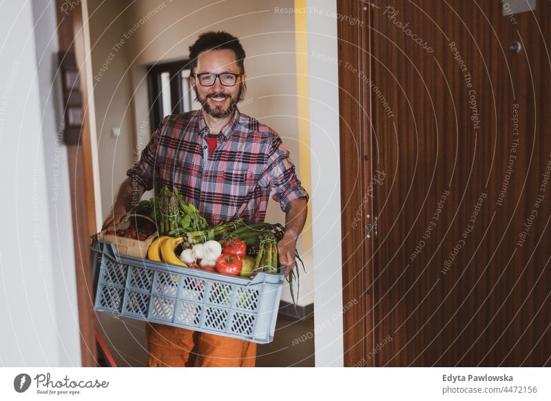 Mann, der eine Obst- und Gemüsekiste ausliefert Erwachsener Kasten kaufen Essen zubereiten Coronavirus Kurier Versand Lieferbox Auslieferer Diät Tür