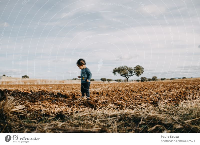 Kind steht auf gepflügtem Feld gepflügtes Feld Kindheit authentisch Kaukasier 1-3 Jahre eine Person Lifestyle Farbfoto Leben Mensch Freude Glück