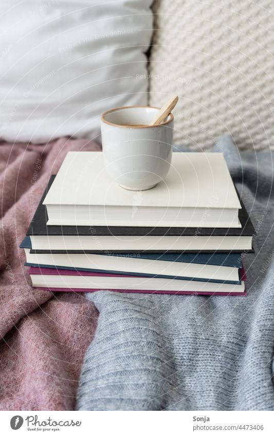 Eine Tasse Kaffee auf einem Bücherstapel im Bett Frühstück Morgen heiß Koffein Getränk Espresso trinken aromatisch Kaffeepause Wolldecke zuhause Hygge lesen