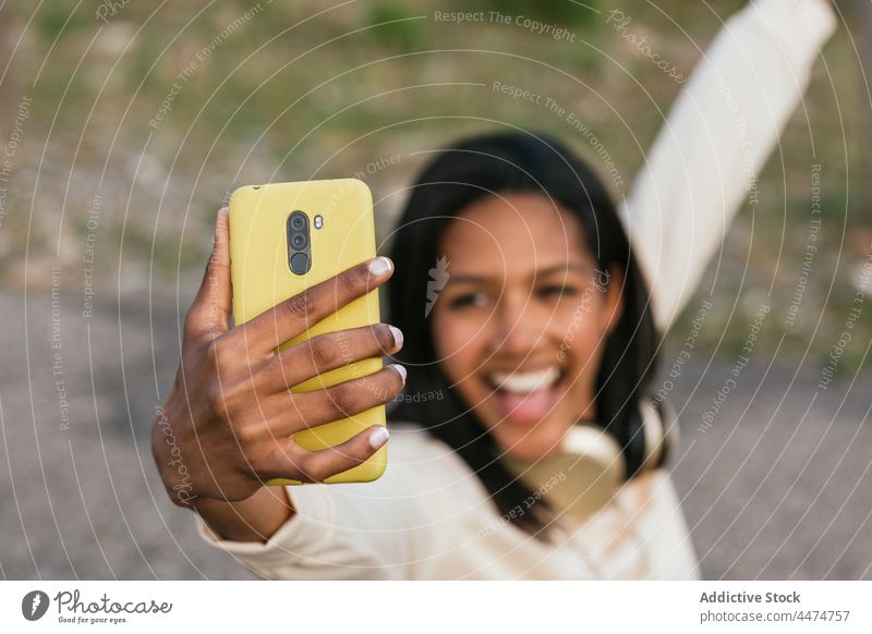 Ethnische Frau auf Longboard macht Selfie mit Smartphone Spaß benutzend Freude Hobby Glück Zahnfarbenes Lächeln Freizeit zeigen Optimist Aktivität Gerät