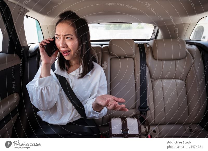 Verwirrte asiatische Frau, die auf dem Rücksitz im Auto telefoniert Passagier Taxi Dämmerung Smartphone benutzend unglaublich Reaktionen u. Effekte verwirren