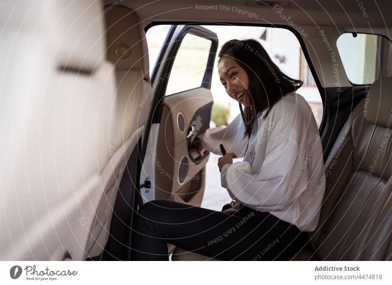 Lächelnde asiatische Frau, die in ein Taxi steigt Passagier betreten Rücksitz positiv Kabine formal PKW Tür offen Abheben Dienst Öffentlich Mitfahrgelegenheit