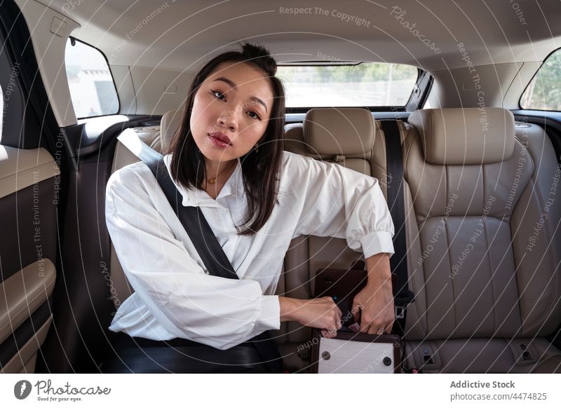 Asiatische Frau öffnet Tasche auf dem Rücksitz eines Taxis Passagier offen Kabine Mitfahrgelegenheit Sicherheit befestigen Gurt PKW Leder Automobil Verkehr Sitz