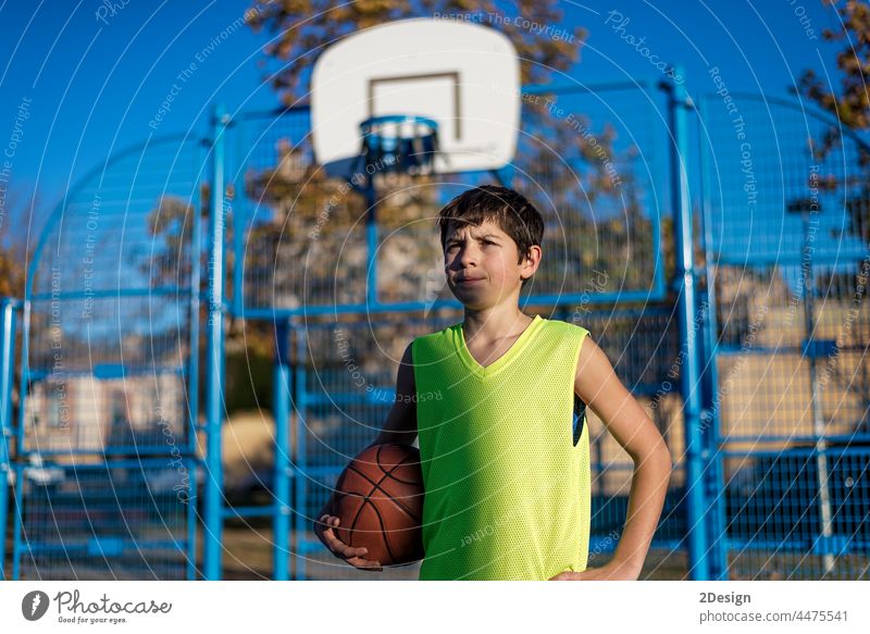 Teenager-Junge hält einen Basketball auf einem Platz. Aktivität Kaukasier Stadtstraße Gericht Lifestyle männlich mittlerer Erwachsener modern im Freien Porträt