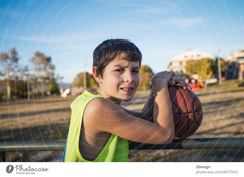 Junger Teenager mit ärmellosem Oberkörper steht auf einem Basketballplatz und lächelt in die Kamera Lächeln Gericht Spieler wirklich Jugend Stehen passen Glück