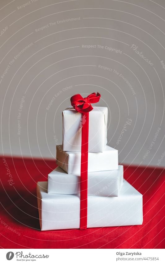 Weiße Weihnachtsgeschenkboxen mit roter Schleife auf rotem Tisch. Weihnachten weiß Geschenk Kasten präsentieren Überraschung Samt Bändchen gebunden sehr wenige