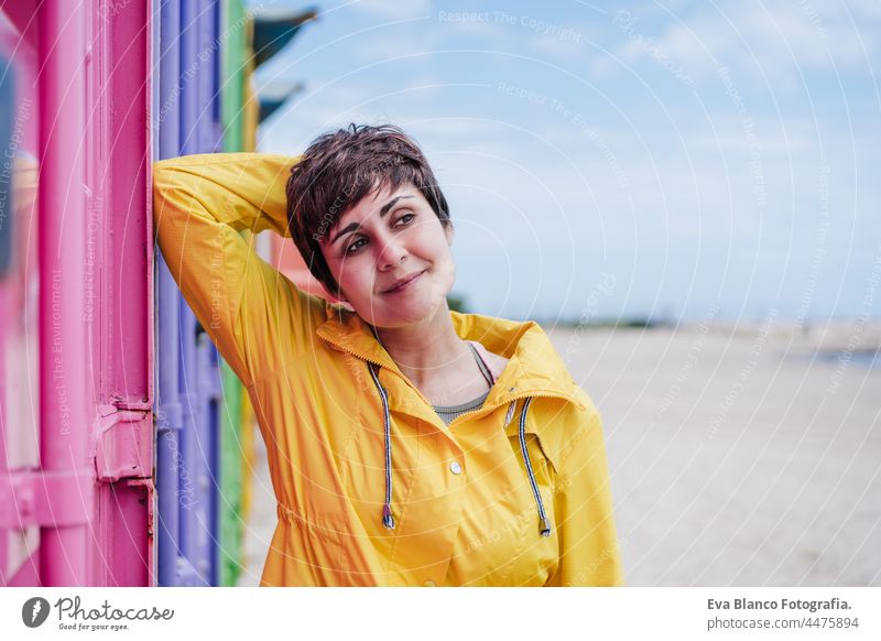 Seitenansicht von entspannten Frau trägt gelben Regenmantel über rosa und lila Hintergrund. Bunte Lebensstil im Freien Porträt farbenfroh Großstadt urban schön