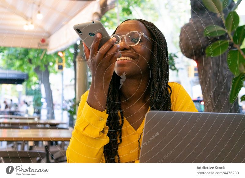 Fröhliche schwarze Frau, die eine Sprachnachricht aufnimmt Stimme Nachricht Smartphone Aufzeichnen Audio Kommunizieren Café Anschluss sprechen Afroamerikaner
