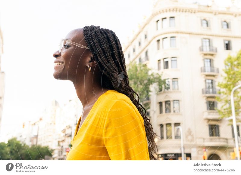 Fröhliche schwarze Frau auf der Straße urban Großstadt Gebäude Revier Freizeit Vorschein Viertel Stil positiv Afroamerikaner heiter Lächeln Glück froh Optimist