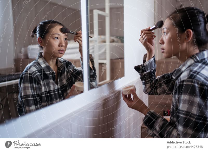 Junge Frau, die sich vor dem Spiegel schminkt Make-up Schlafzimmer Pulver Vorschein Reflexion & Spiegelung Routine Licht heimwärts asiatische Frau ethnisch jung