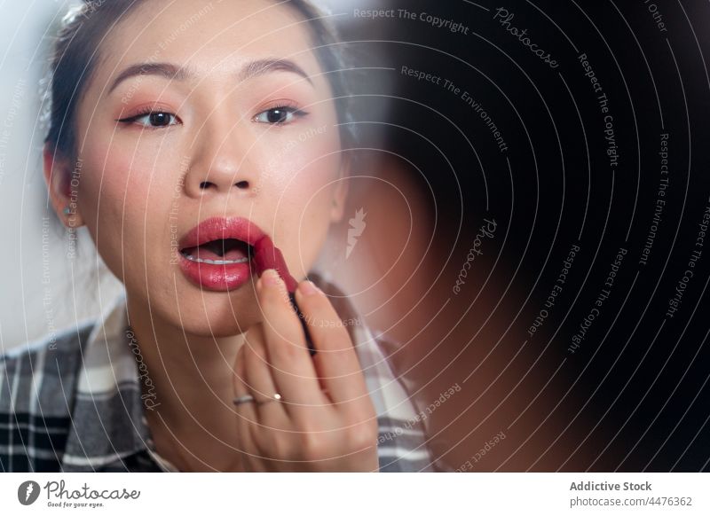 Charmante Frau trägt hellen Lippenstift auf Spiegel Make-up Kosmetik Reflexion & Spiegelung Vorschein Routine Gesicht Stil bewerben asiatische Frau ethnisch