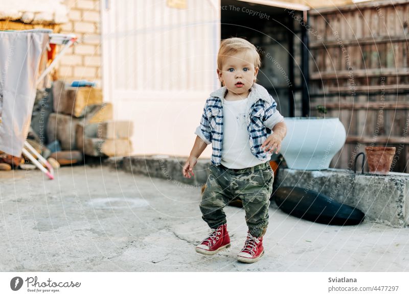 Ein charmanter kleiner Junge geht im Hinterhof eines Bauernhofs spazieren wenig Scheune Hintergrund kleiner Bauer Kind Baby Gebäude im Freien niedlich weiß jung