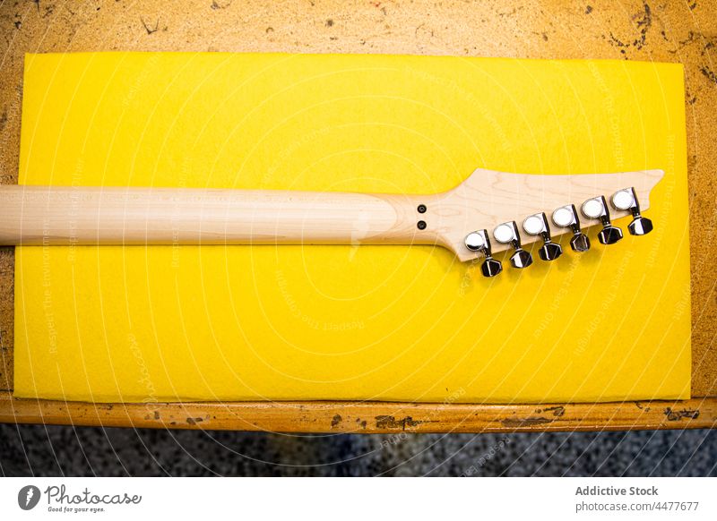 Hölzerner Gitarrenhals gegen gelbes Blatt Papier Instrument Musik Oberfläche neu hölzern Spindelstock Detailaufnahme Stimmwirbel Tisch Gerät Objekt Design Hals