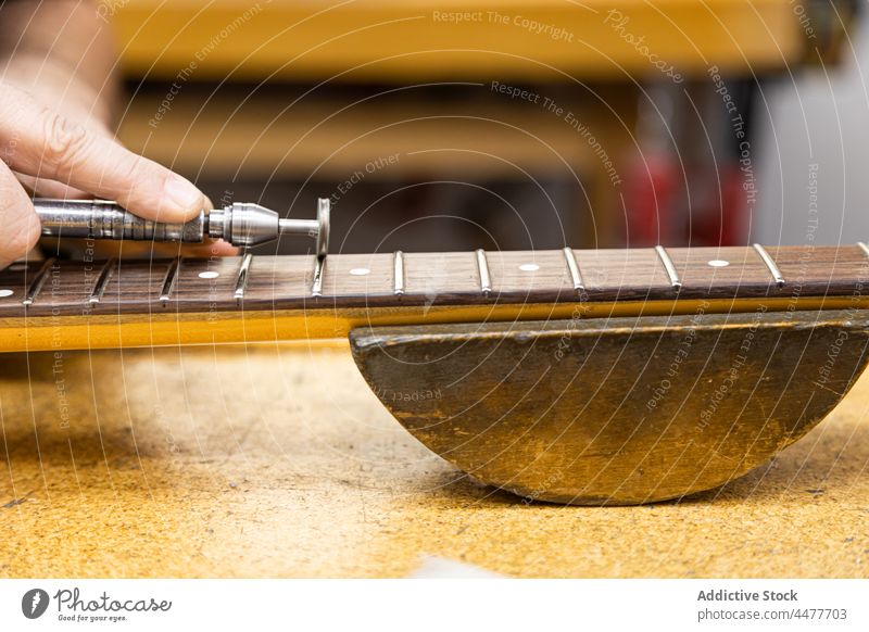 Unbekannter Geigenbauer poliert Bünde in der Werkstatt Meister Zupfinstrumentenmacher polnisch ärgern Gitarre Instrument Reparatur Gerät Hals Werkzeug