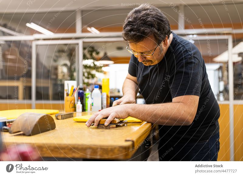 Handwerker schleift Gitarrenhals in der Werkstatt Kunsthandwerker Grinden Griffbrett Fähigkeit Instrument Gerät professionell Mann Meister Holz stehen Tisch