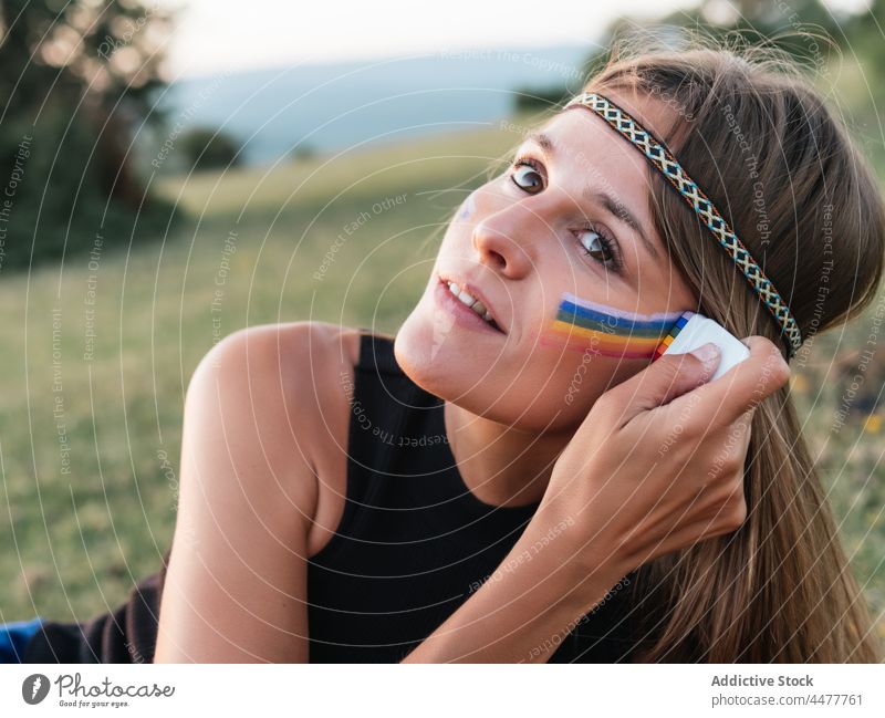Frau malt Regenbogen auf Gesicht mit einem Stock Hippie Freiheit lgtbi lgtbiq Lebensstile Farbe Frieden purpur Liebe magenta Menschen retro lesbisch Farbbild