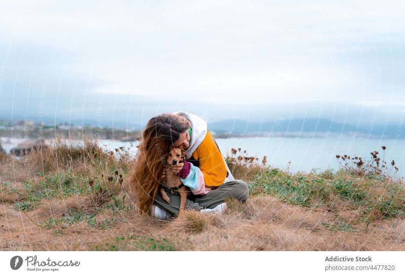 Frau mit verspieltem Hund an der Küste Kuss Gesicht Streicheln Strand Reisender Zusammensein Lächeln Hochland Ufer Umarmung Domstrand