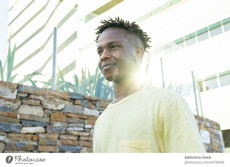 Schwarzer Mann steht in der Nähe einer Steinmauer positiv sorgenfrei Wand Optimist Typ schwarz Lachen trendy lässig Glück Afroamerikaner Freude zufrieden