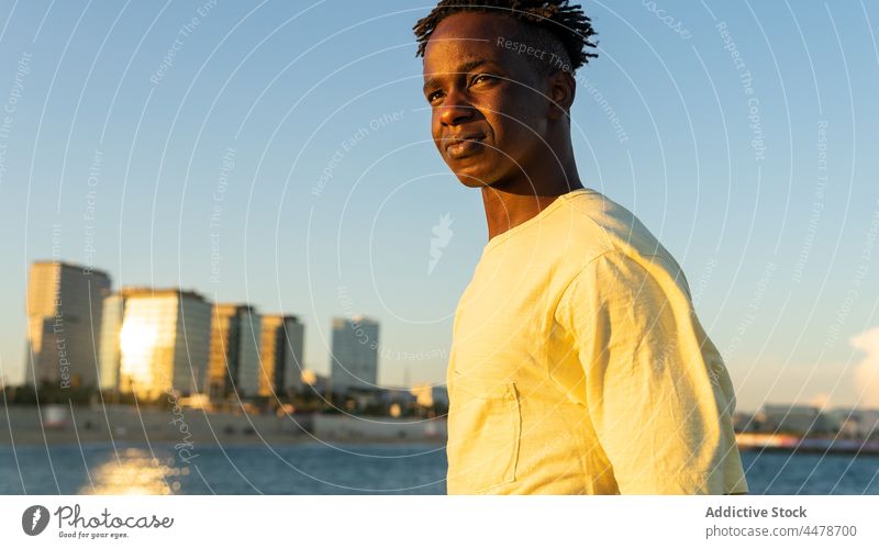 Schwarzer Mann schaut auf der Straße weg Himmel Sonnenuntergang Windstille Meer Gebäude Abend friedlich Outfit Großstadt MEER männlich Afroamerikaner schwarz