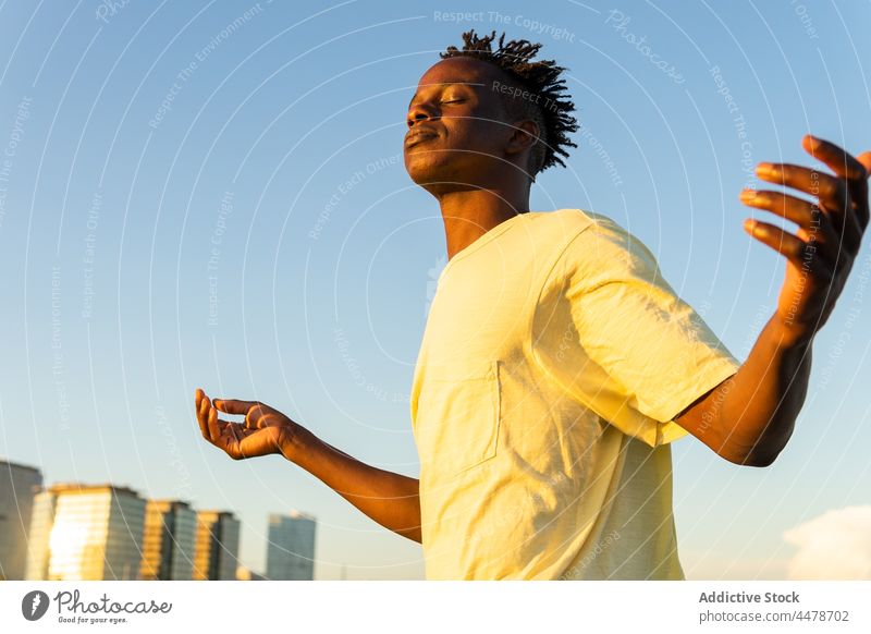 Schwarzer Mann mit erhobenen Armen auf der Straße Himmel Sonnenuntergang Windstille Gebäude Abend friedlich Outfit Großstadt männlich Afroamerikaner schwarz