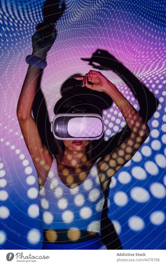 Coole Frau erkundet virtuelle Realität mit Neonbrille Illumination Schutzbrille VR Tanzen Projektor unterhalten eintauchen cool neonfarbig benutzend Apparatur