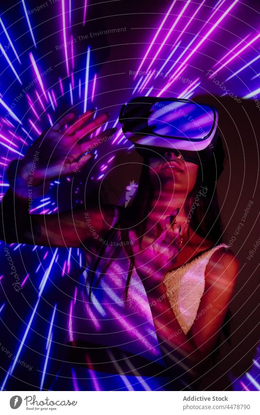 Frau mit VR-Brille in Neonlicht Virtuelle Realität Schutzbrille eintauchen Illumination Erfahrung unterhalten Technik & Technologie Projektor freie Zeit Licht