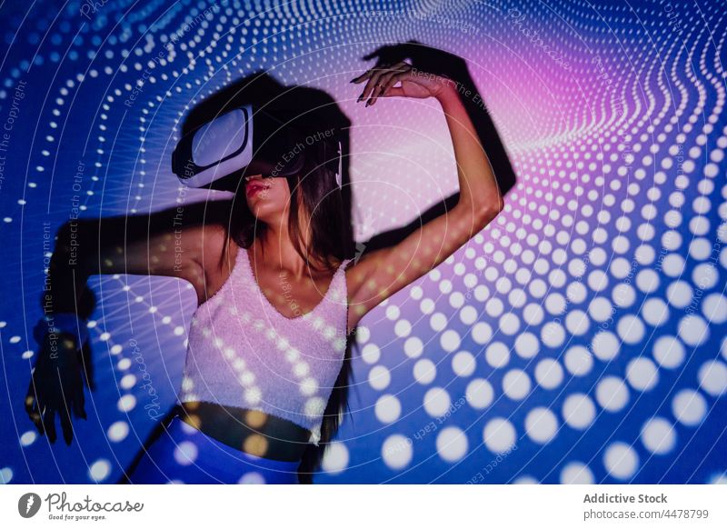 Coole Frau erkundet virtuelle Realität mit Neonbrille Illumination Schutzbrille VR Tanzen Projektor unterhalten eintauchen cool neonfarbig benutzend Apparatur