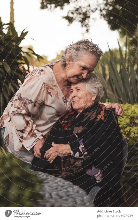 Ältere Frau küsst Schwester auf den Kopf Frauen Kuss Garten Glück Umarmung Liebe Angebot Zusammensein Wochenende älter gealtert Senior Lächeln Umarmen Park