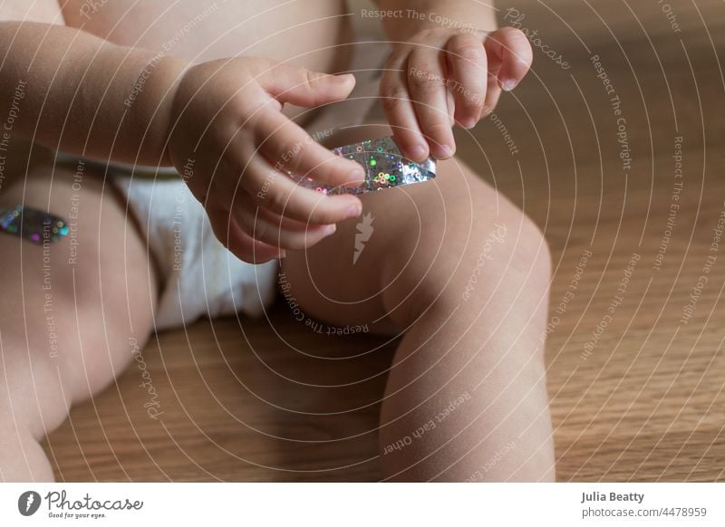 15 Monate altes Baby spielt mit einem Verband, nachdem es in beide Beine geimpft wurde Impfung Impfstoff impfen behüten immun Booster bandagieren Pflaster