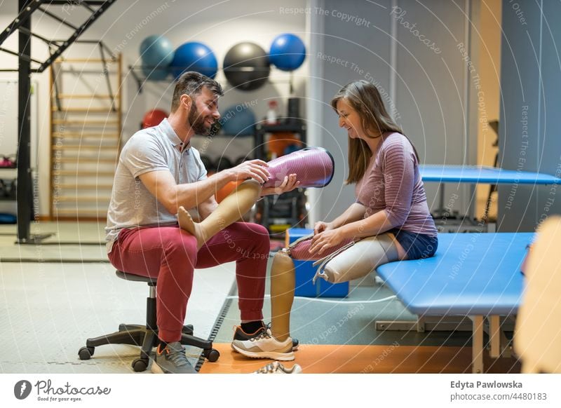 Frau mit Beinprothese im Gespräch mit einem Physiotherapeuten Physiotherapie Tatkraft Wiederherstellung Rehabilitation Stärke Training Beine Übung Fitness Sport