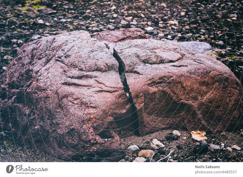 natürlich gespaltener roter Felsblock an der Ostseeküste. Kleine Felsen und Kieselsteine um abstrakt Hintergrund Strand schön Felsbrocken gebrochen braun