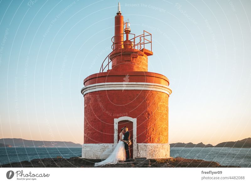 Leuchtturm mit einem frisch verheirateten Paar an seiner Tür Hochzeit Ehemann Ehefrau Bekleidung Liebe Textfreiraum Meer MEER heterosexuell Braut striegeln
