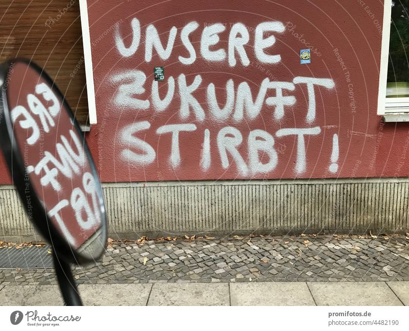 Spiegelung, Graffiti auf roter Hauswand "Unsere Zukunft stirbt!" / Foto: Alexander Hauk Mauer hauswand silber silberfarben kunst straßenkunst vandalismus