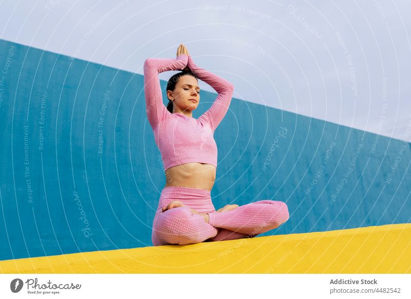 Frau mit geschlossenen Augen beim Yoga Lotus-Pose Sportkleidung üben Windstille Harmonie Asana Gesundheit friedlich Barfuß passen Wohlbefinden padmasansa jung