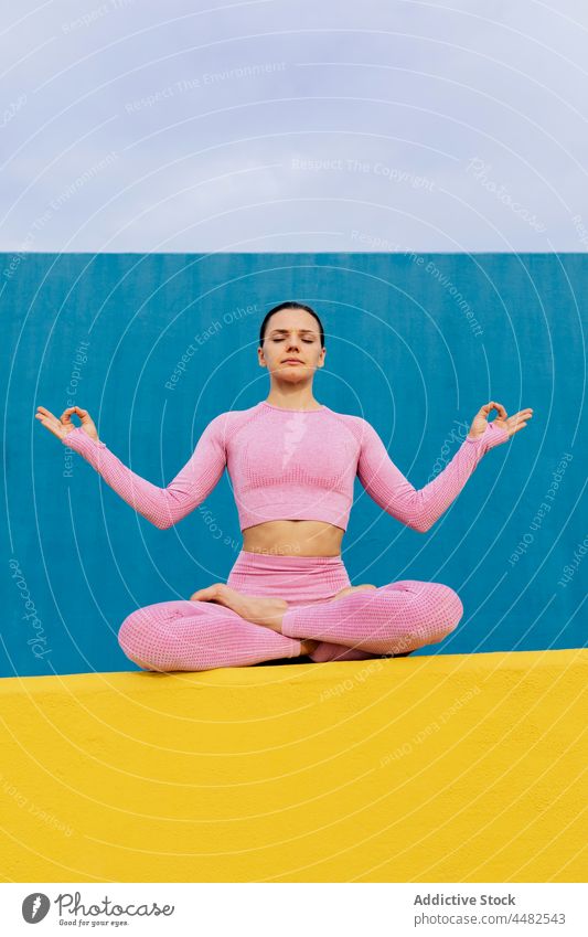 Ruhige Frau sitzt und meditiert Lotus-Pose Windstille meditieren Wellness Harmonie Sportkleidung friedlich üben Zen Yoga sich[Akk] entspannen Gesundheit jung